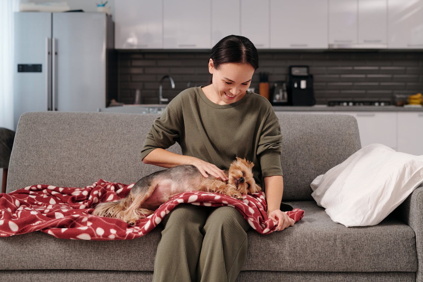 Gardienne caressant un chien sur un canapé pour une garde d’animaux à domicile